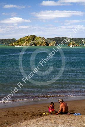 People on the beach at Bay of Islands at the town of Paihia, North Island, New Zealand.