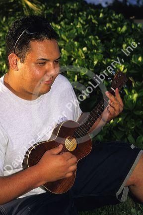 A hawaiian teen plays the ukalele.