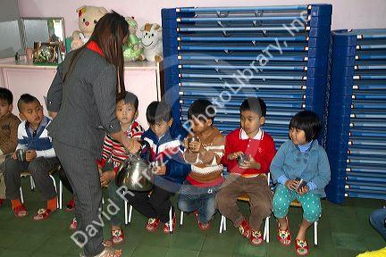 Young students recieve hot water for noodles at an elementary school in Da Lat, Vietnam.