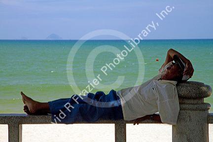 Man taking a nap on a bench at the beach in Nha Trang, Vietnam.