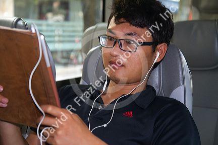 Young vietnamese man using a tablet computer on a bus in Hanoi, Vietnam.