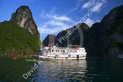 Tour boat and tourists using sea kayaks in Ha Long Bay, Vietnam.