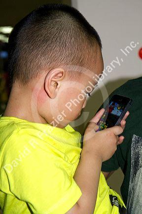 Vietnamese boy playing games on an iphone in Ho Chi Mihn City, Vietnam.