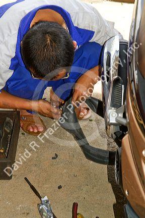 Sidewalk mechanic fixing a flat tire on a scooter in Da Lat, Vietnam.