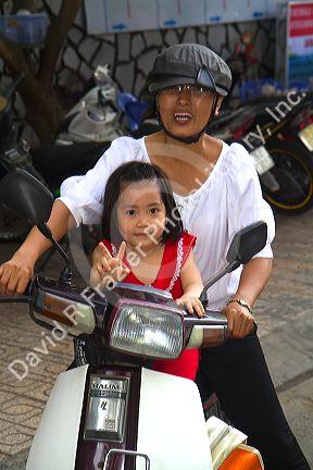 Mother and child riding a motor scooter together in Nha Trang, Vietnam.