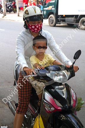 Mother and child riding a motor scooter together in Nha Trang, Vietnam.