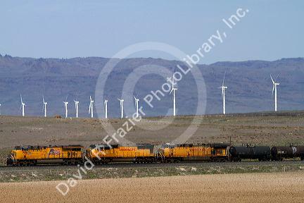 Union Pacific Railroad train traveling past a line of wind powered electric generators in Elmore County, Idaho, USA.
