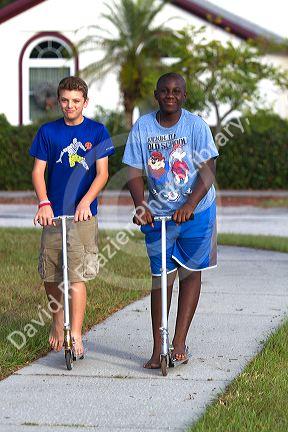 Two 11 year old boys riding scooters in Florida, USA.