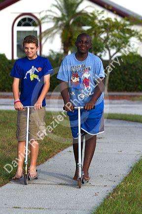 Two 11 year old boys riding scooters in Florida, USA.