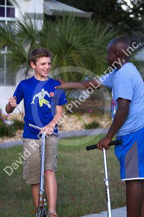 Two 11 year old boys riding scooters in Florida, USA.