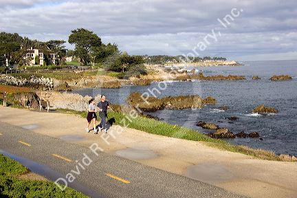 People jogging along the rocky shore in Monterey, California.