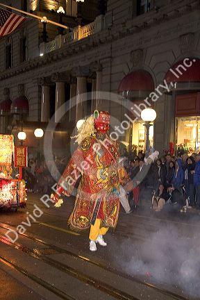 Chinese giant marches in the Chinese New Year Parade, San Francisco, California as firecrackers explode.