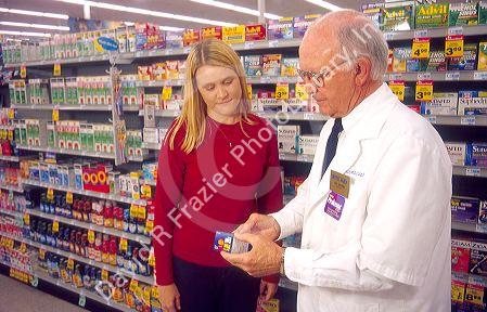 Pharmacist showing customer cold medicine in a drug store. MR