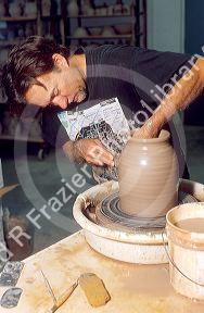 Potter using clay on a potters wheel.