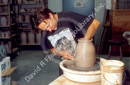 Potter using clay on a potters wheel.
