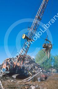 Electromagnetic crane picking up metal in a salvage yard.