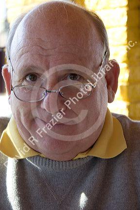 A portrait of a fifty eight year old man wearing glasses.