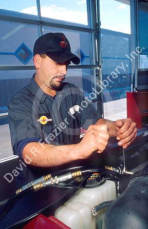 An auto mechanic working on a car uses wrenches to make repairs.