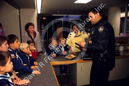 A police officer speaks to boy Scouts on a field trip to a police station.