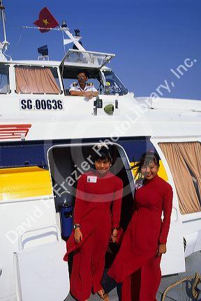 A hydrofoil boat crew on the Saigon River in Vietnam. Vietnamese women wear ao dai.