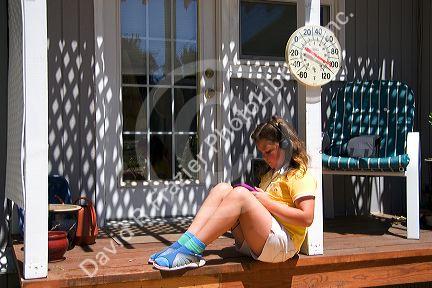 Nine year old girl listening to a walkman, personal cd player in 100 degree weather.