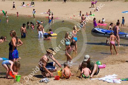 Adults and children play on the beach and in the water at Sandy Point near Boise, Idaho.