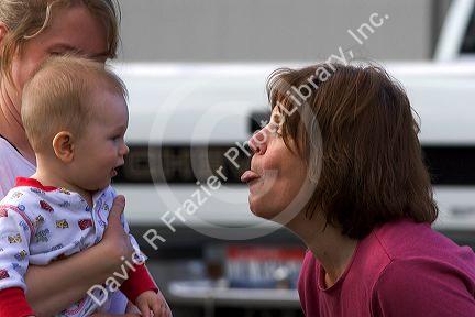 Woman sticking her tongue out at a baby to make it laugh.