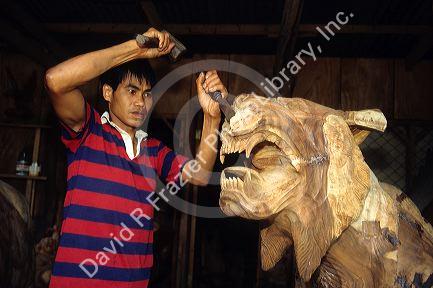 A woodcarver working with chisel and hammer in the Philippines.