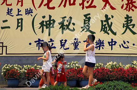 Children walk past a sign with Chinese characters in Taipei, Taiwan.