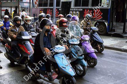 People wearing helmets ride motorscooters in Taipei, Taiwan.