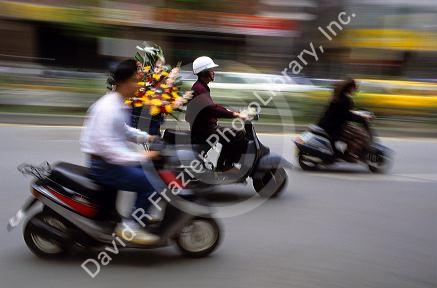 People riding scooters in Taipei, Taiwan.  Flower delivery man uses scooter.