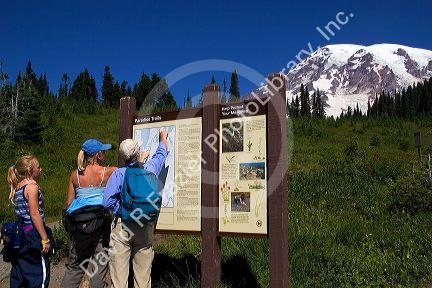Hikers look at map of Mt. Rainier in Mt. Rainier National Park, Washington.