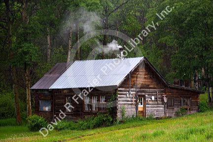 Log cabin with smoke coming out of chimney in the mountains of British Columbia, Canada.