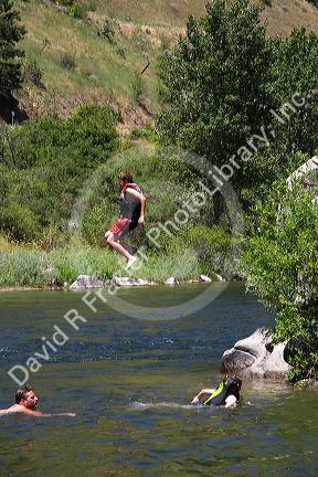 A boy wearing a lifejacket jumps off of a rock into the Payette River near Horseshoe Bend, Idaho.