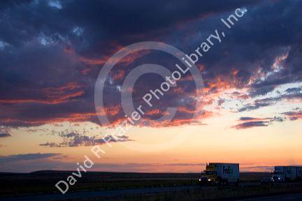 Automobiles and long haul trucks driving with headlights on at sunset on Interstate 84 east of Boise, Idaho.