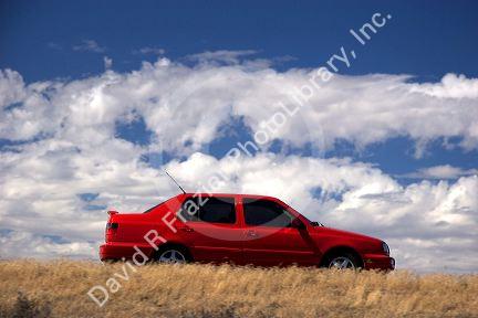 Red automobile traveling on the highway.