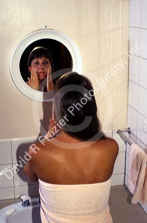 Young woman uses a mirror while washing her face. MR