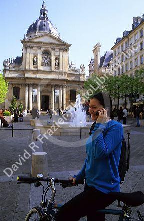 A french woman using a cell phone in front of the Sorbonne in Paris, France.