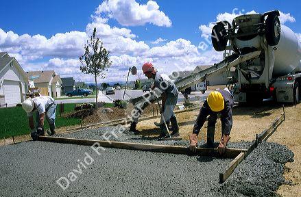 Workers pouring concrete and screeding it to make a driveway in a subdivision in Idaho.