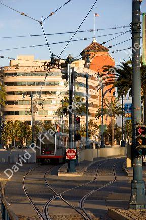 A street car traveling on tracks in San Francisco, California.  Overhead wires provide electricity to the cars.