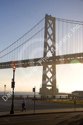 Foggy sunrise with the Bay Bridge backlit by the sun in the morning, San Francisco, California.