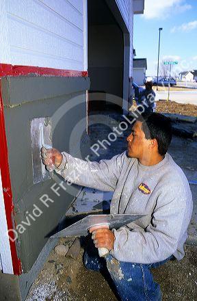 A worker applying stucco to a new home.