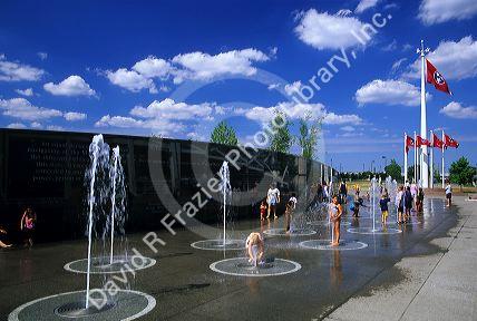 Children play in water fountains in front of the Tennessee River story wall at the Capitol Mall in Nashville, Tennessee.