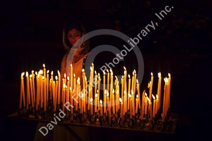 A woman lighting prayer candles inside a Catholic Church in Italy.