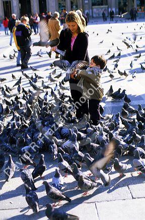 A mother and son feeding pigeons in front of the Duomo in Milan, Italy.