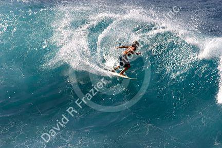 Surfing on waves in the pacific ocean off the island of Maui, Hawaii.