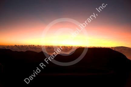 Sunrise above the clouds on the island of Maui, Hawaii atop Mount Haleakala.