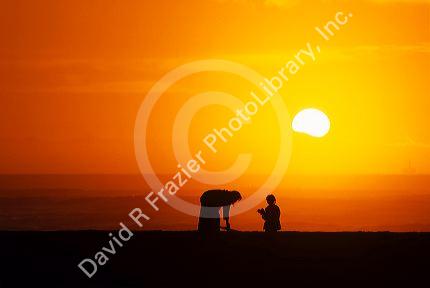 Silhouette of a woman and child on the beach at sunset.