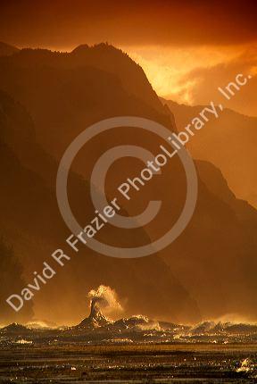 Waves crash at sunset along the Kaui coast cliffs in Hawaii.