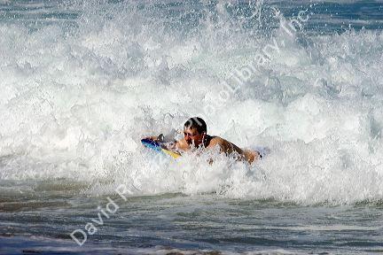 Boogie boarding on waves in the pacific ocean off the island of Maui, Hawaii.